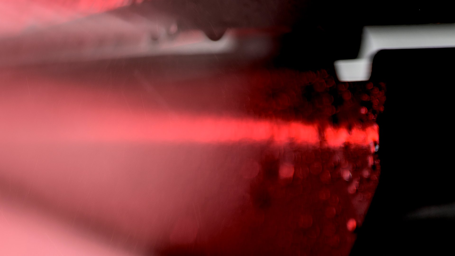 Abstract close-up of illuminated red vehicle light with water droplets