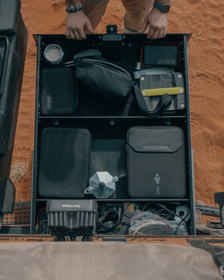 Open vehicle drawer system organized with tools, camping gear, and accessories.