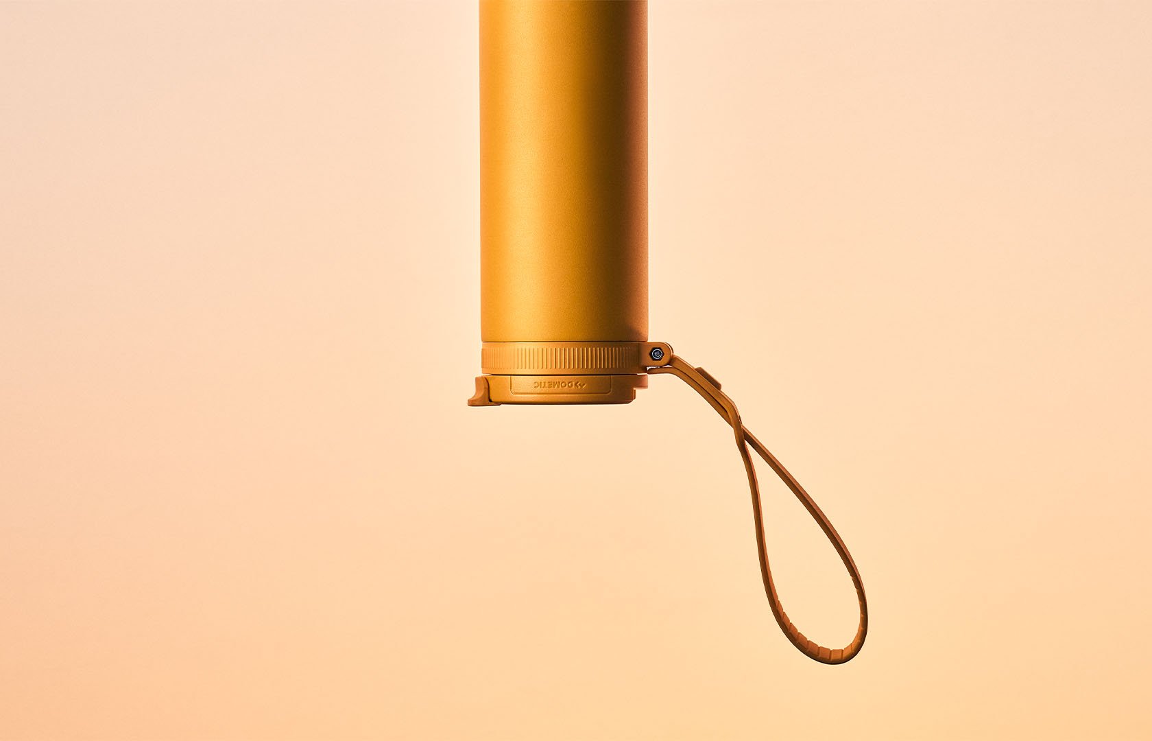 Yellow insulated thermo bottle hanging upside down with strap against a warm gradient background.